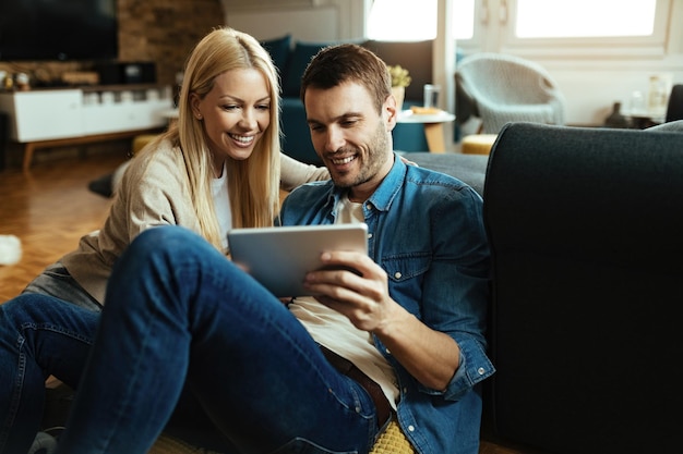 Pareja feliz usando tableta digital mientras se relaja en la sala de estar