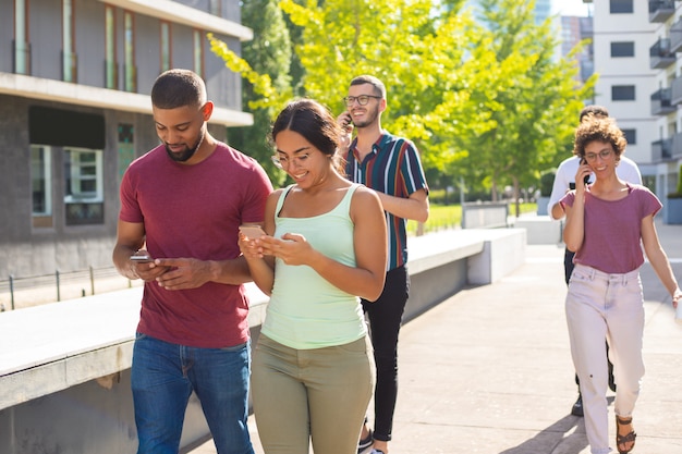 Pareja feliz usando teléfonos móviles al aire libre