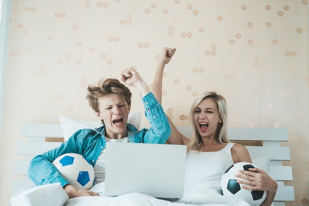 Pareja feliz viendo fútbol soccer en la cama