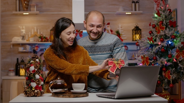 Pareja festiva dando regalos en videoconferencia