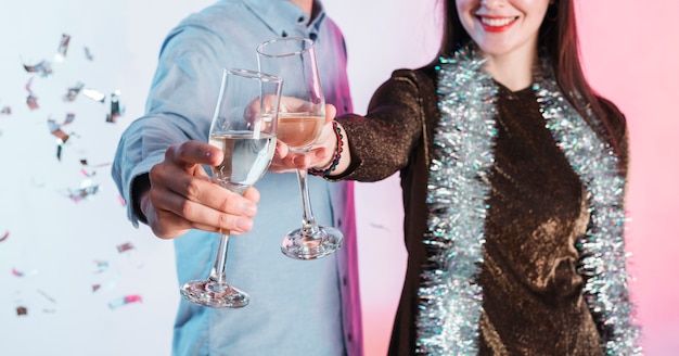Foto gratuita pareja festivamente vestida tintineando copas de champán