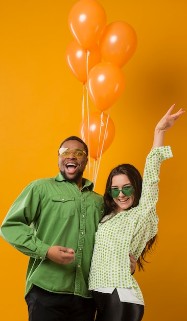 Pareja en fiesta divirtiéndose y sosteniendo globos