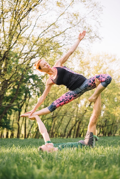 Foto gratuita pareja flexible practicando acro yoga en el parque