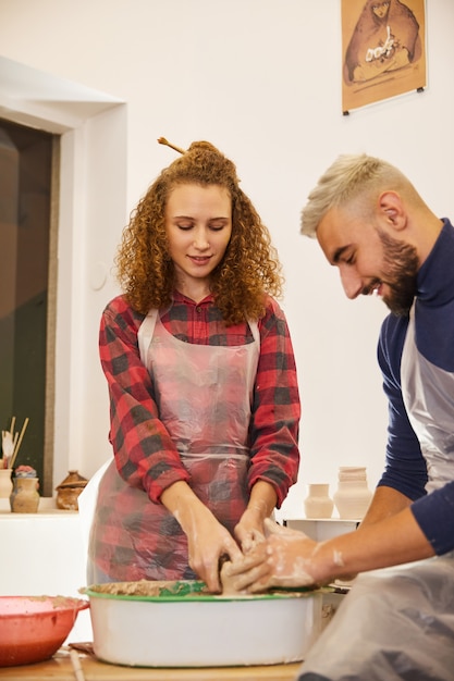 Pareja forma un jarrón en un lugar de trabajo de cerámica