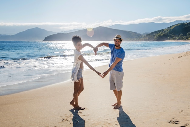 Pareja formando corazón en la playa