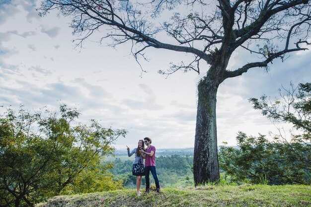 Pareja en frente de un árbol en una colina