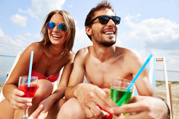 Pareja con gafas de sol y cóctel en la playa