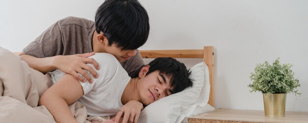 Pareja gay asiática beso y abrazo en la cama en su casa. Jóvenes asiáticos LGBTQ hombres felices relajarse descansar juntos pasar tiempo romántico después de despertarse en el dormitorio en casa por la mañana.