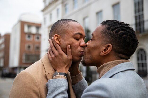 Pareja gay compartiendo un beso al aire libre en la ciudad
