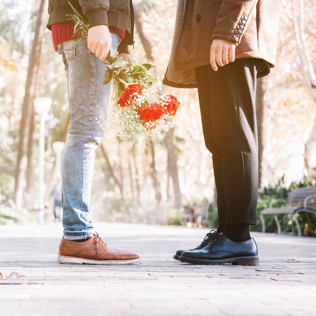 Pareja gay de cultivos con flores en el parque