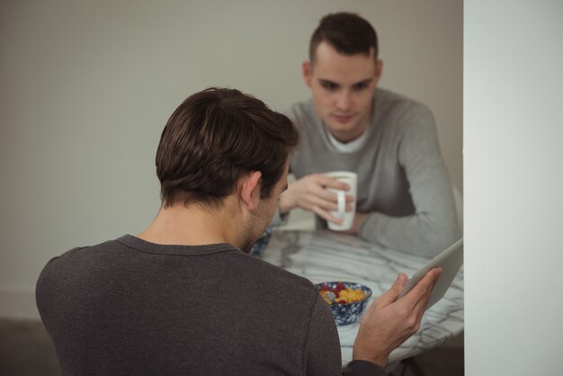 Una pareja gay mirando tableta digital mientras desayuna