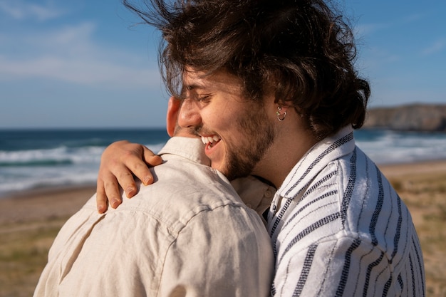 Foto gratuita pareja gay de plano medio en la playa