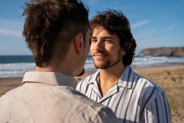 Foto gratuita pareja gay de plano medio en la playa