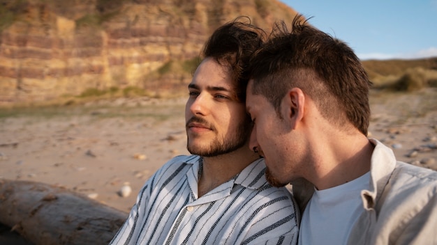 Foto gratuita pareja gay de plano medio en la playa