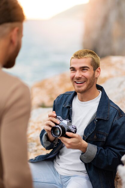 Pareja gay en la playa con cámara