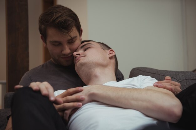 Una pareja gay romántica abrazada en un sofá en el salón