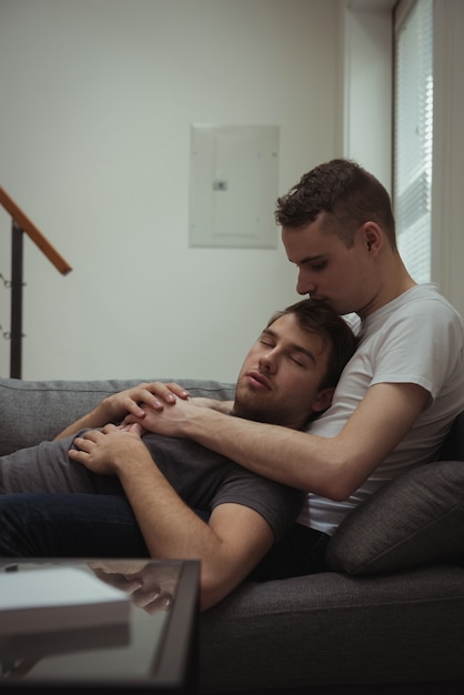 Pareja gay romántica relajándose en el sofá en la sala de estar