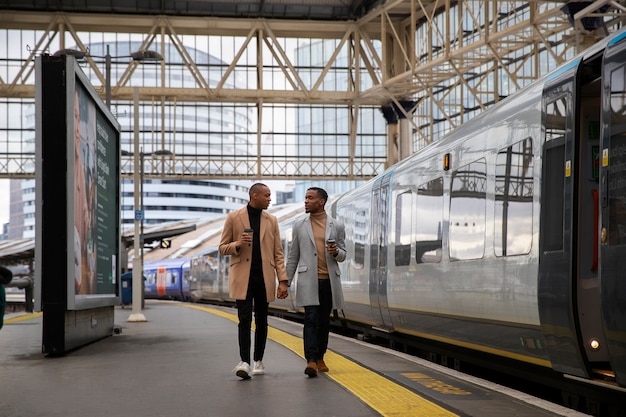 Foto gratuita una pareja gay tomados de la mano en la estación de tren durante una cita