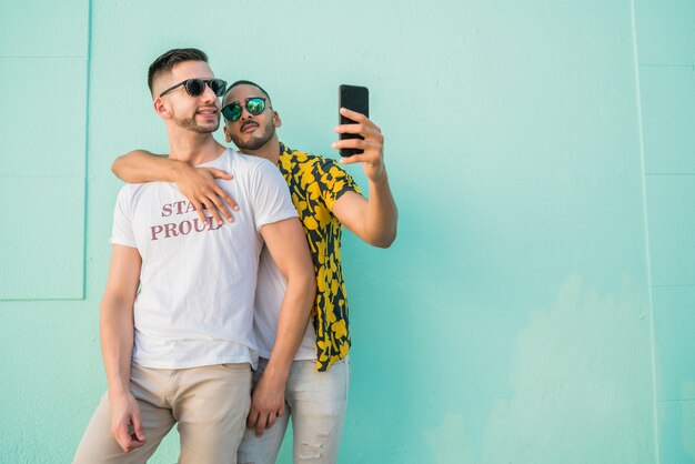 Pareja gay tomando un selfie con teléfono móvil.