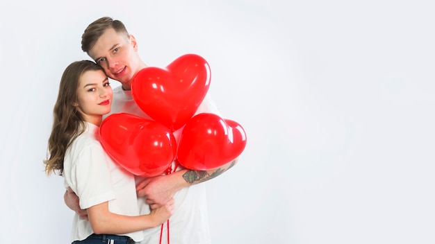 Pareja con globos de corazón abrazando