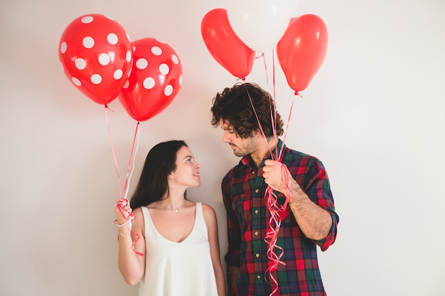 Pareja con globos en las manos mirándose a los ojos