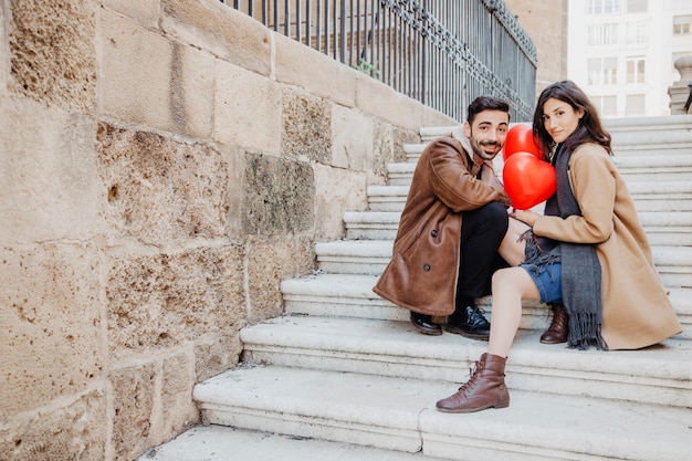 Pareja con globos posando en las escaleras