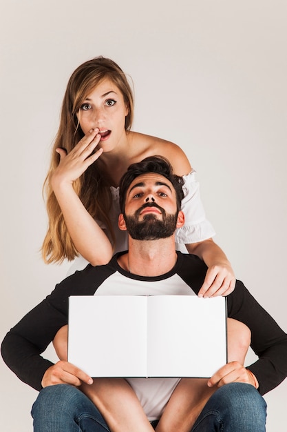 Pareja graciosa mostrando libro en blanco