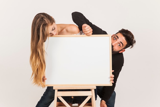 Foto gratuita pareja graciosa con tabla en blanco