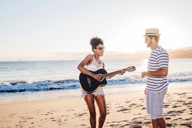 Pareja con guitarra en la orilla