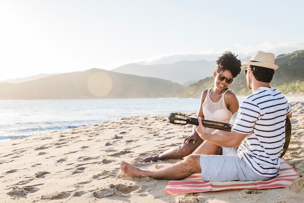 Foto gratuita pareja con guitarra en la playa