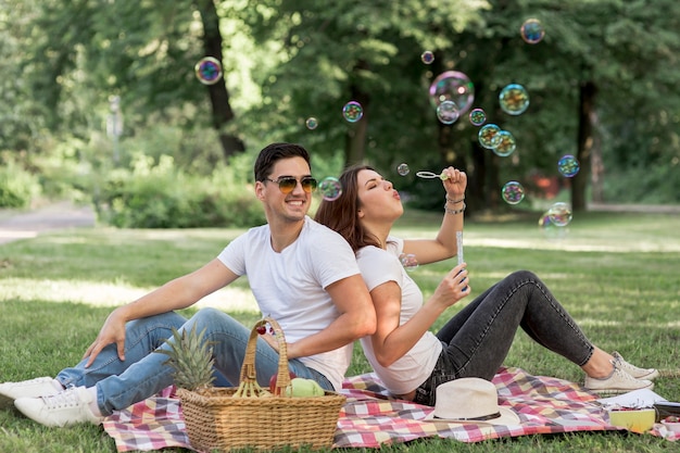 Pareja haciendo burbujas sentadas espalda con espalda