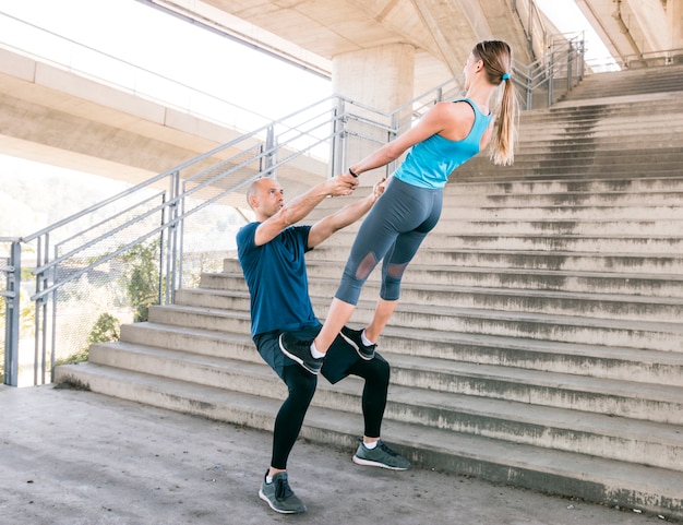 Pareja haciendo ejercicio entrenamiento aeróbicos postura cerca de la escalera