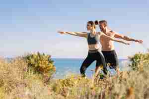 Foto gratuita pareja haciendo ejercicio de equilibrio en la playa