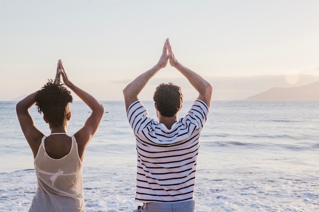 Foto gratuita pareja haciendo ejercicio de yoga en la playa