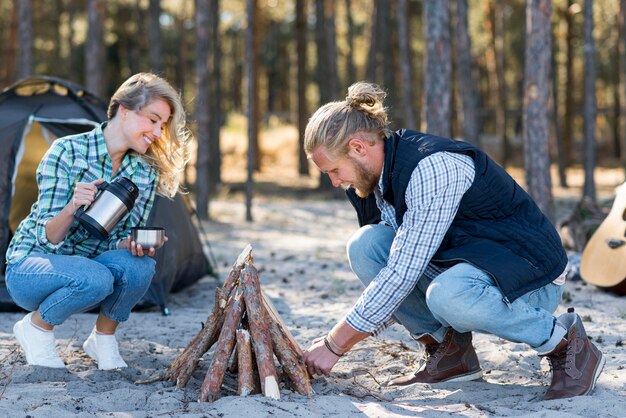 Pareja haciendo una fogata en la naturaleza