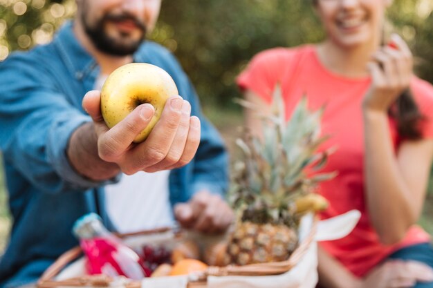 Pareja haciendo un picnic hombre enseñando manzana