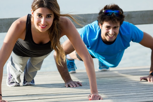 Foto gratuita pareja haciendo push ups cerca del mar