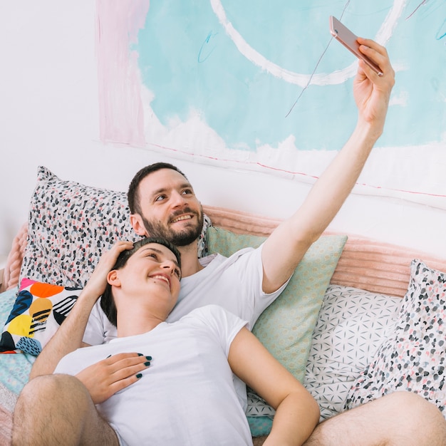 Pareja haciendo selfie en la cama