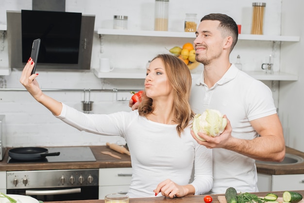 Foto gratuita pareja haciendo selfie en cocina