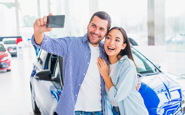 Pareja haciendo selfie en concesionario de coches