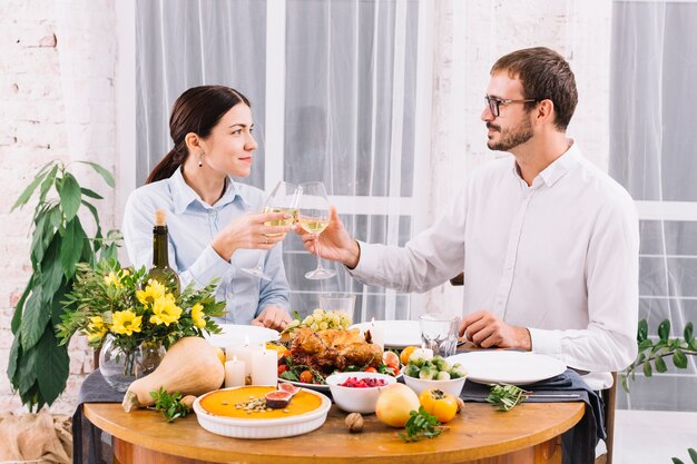 Pareja haciendo sonar las copas en la mesa