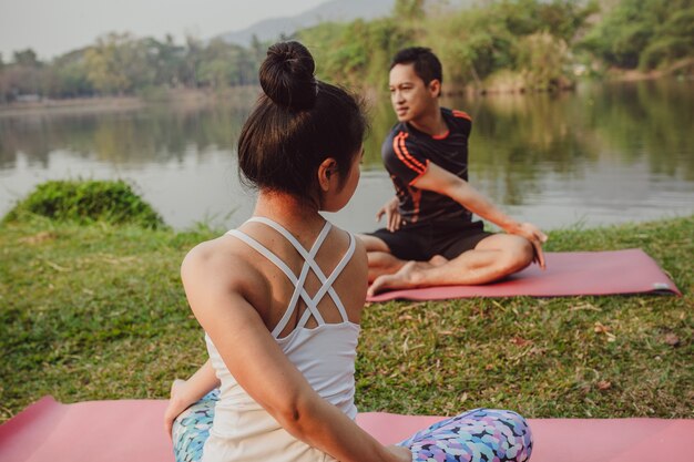 Pareja haciendo yoga al lado del lago