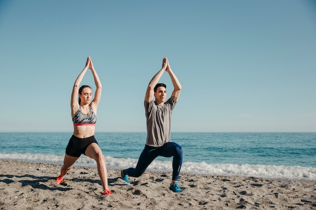 Pareja haciendo yoga en la playa