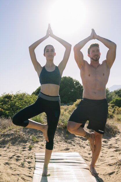 Pareja haciendo yoga en el sol