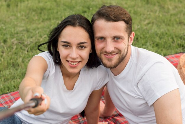 Foto gratuita pareja haciéndose un selfie en manta de picnic