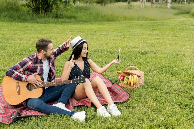 Pareja haciéndose un selfie sobre manta de picnic