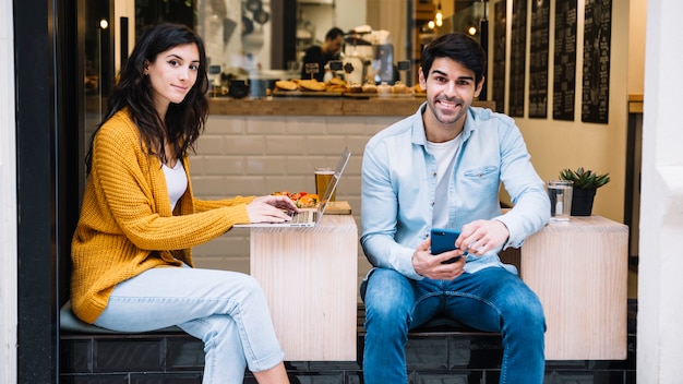 Pareja hispana con dispositivos electrónicos en café