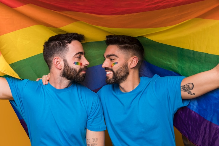 Foto gratuito pareja de hombres homosexuales abrazando en la bandera del arco iris