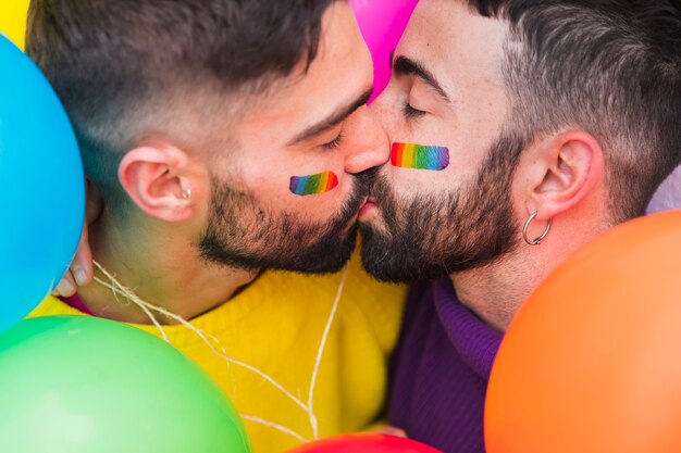 Pareja de homosexuales besándose con los ojos cerrados.