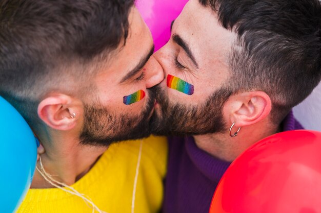 Pareja de homosexuales besándose con los ojos cerrados.